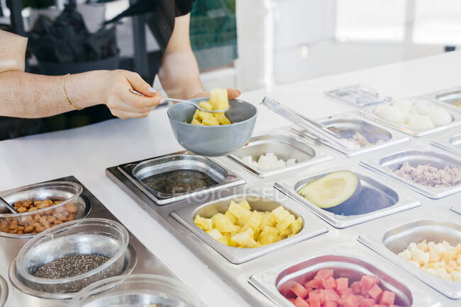 Anonimo donna matura scegliendo deliziosa frutta da contenitori in metallo mentre self service in ristorante contemporaneo — Foto stock