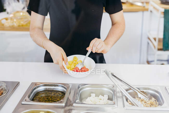 Анонімна зріла жінка вибирає смачні фрукти з металевих контейнерів під час самообслуговування в сучасному ресторані — стокове фото