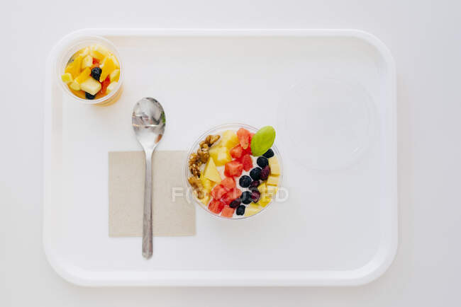 Зверху миски з йогуртом і фруктами поміщають на піднос з ложкою і серветкою в кафе самообслуговування — стокове фото