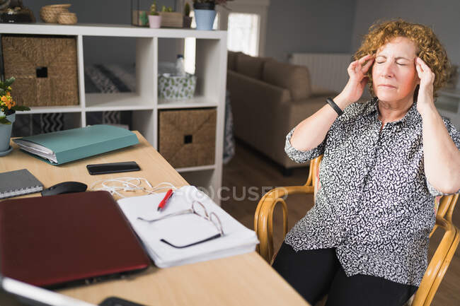 Visão lateral da mulher adulta focada em roupas casuais desfrutando de música em fones de ouvido com olhos fechados enquanto descansa durante o trabalho em laptop e notebook — Fotografia de Stock