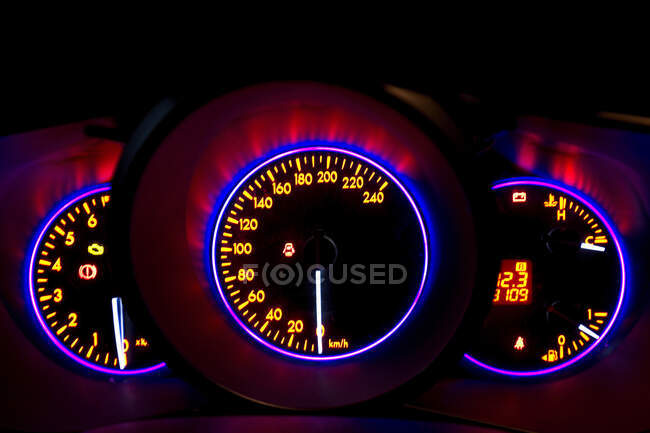 Панель приборов автомобиля с неоновой подсветкой на цифровом дисплее с индикаторами и информацией о скорости — стоковое фото