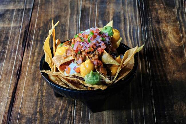 Hohe Winkel der leckeren Vorspeise aus knusprigen Mais-Chips mit Guacamole und Käsesauce auf dem Tisch im Restaurant garniert — Stockfoto