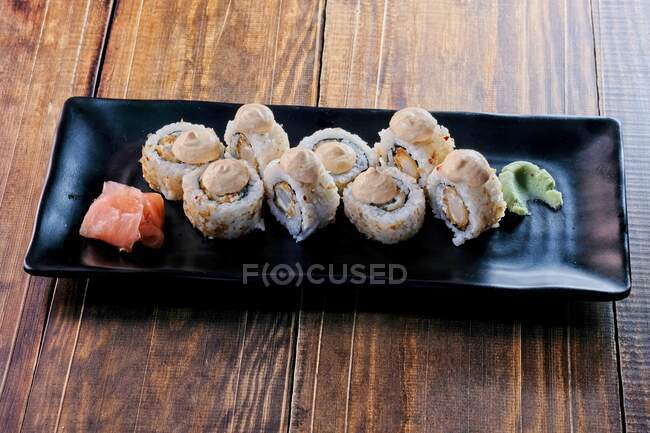 Plate of delicious rolls served with wasabi and cheese sauces and pickled ginger — Stock Photo