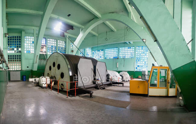 Large gray metal circular machine and yellow instrument room locating inside desert coal mine workshop with green walls illuminated by bright sun from windows — Stock Photo