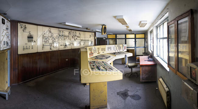 Жовті старі панелі приладів з безліччю датчиків кнопок і циферблатів в контрольній кімнаті з кресленнями і діаграмами на стіні в покинутій будівлі знехтування вугільної шахти — стокове фото