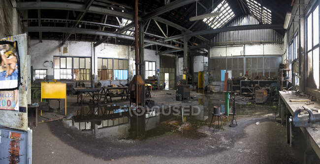 Sala industrial suja abandonada com telhado vazando com bancos de metal várias mesas em ruínas e lixo no prédio da fábrica de carvão deserta — Fotografia de Stock