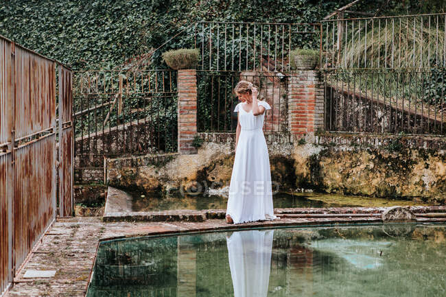 Молодая невеста возле потрепанного забора и бассейна — стоковое фото