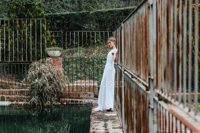 Jeune mariée près d'une clôture et d'une piscine minables — Photo de stock