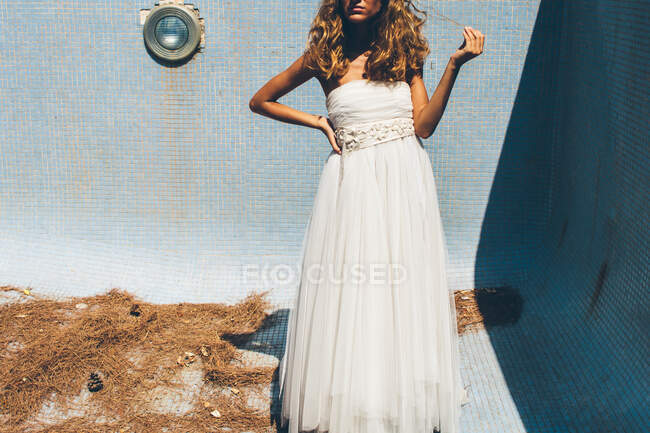 Sensuale giovane sposa in elegante abito da sposa bianco in piedi in piscina vuota — Foto stock