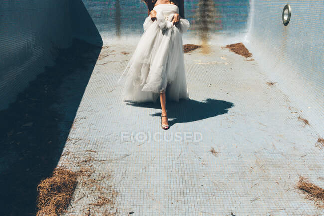 Sensual anonymous bride dancing in empty dirty pool — Stock Photo