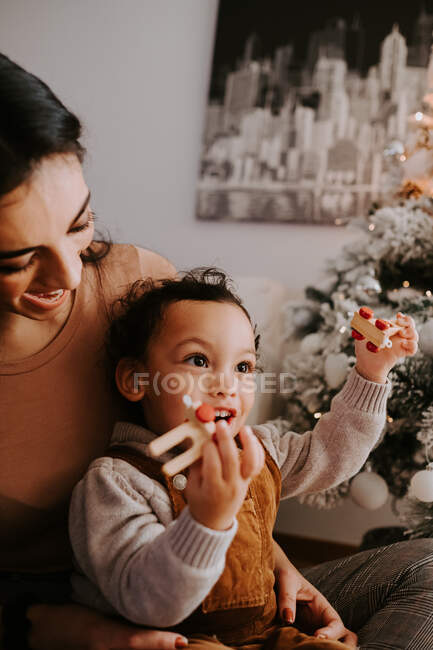 Cheerful loving mother hugging little son sitting on floor near Christmas tree — Stock Photo