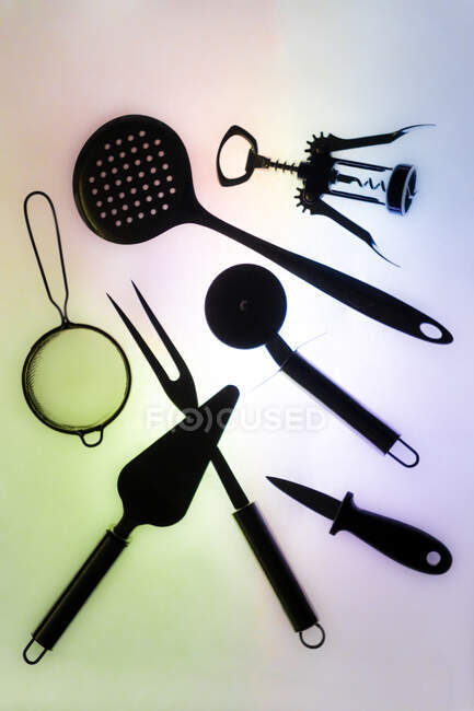 Set von verschiedenen Küchenutensilien zum Kochen und Servieren auf beleuchtetem, buntem Hintergrund — Stockfoto