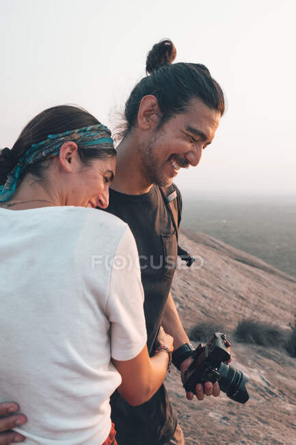 Vista lateral do conteúdo casal de hipsters em roupas casuais abraçando com os olhos fechados enquanto viajam juntos pelo Sri Lanka e tirando fotos de paisagens majestosas — Fotografia de Stock