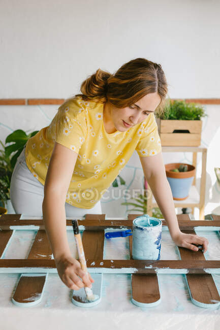 Front view of a young blonde woman painting a fence. — Stock Photo