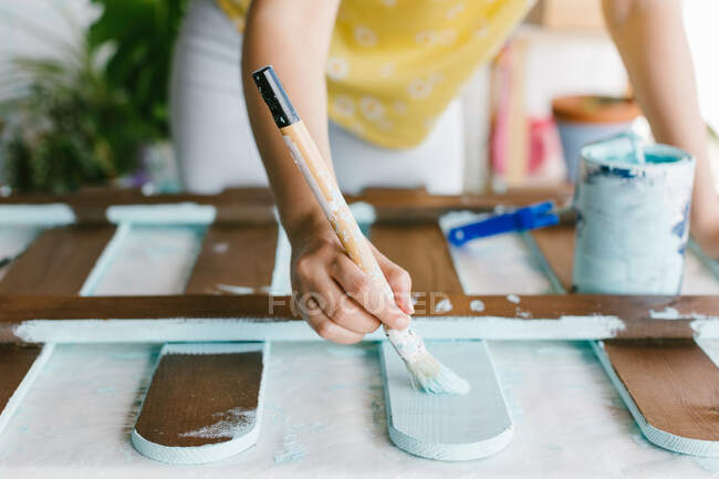 Vista de cerca de una mano de una persona pintando una valla con pintura turquesa. - foto de stock