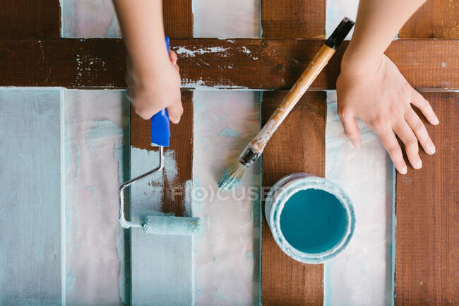 Vista superior de las manos de un caucásico pintando una antigua valla para ser restaurada. - foto de stock
