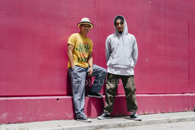 Двоє молодих міських танцюристів, що стоять біля рожевої стіни на вулиці — стокове фото