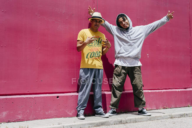 Два молодых городских танцора стоят рядом с розовой стеной на улице — стоковое фото