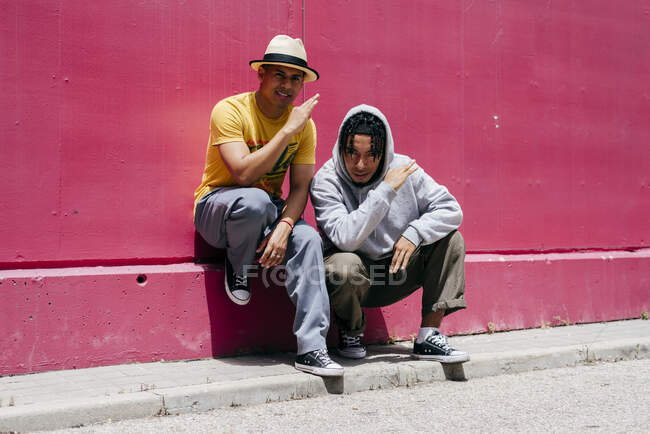 Deux jeunes danseurs urbains debout près d'un mur rose dans la rue — Photo de stock
