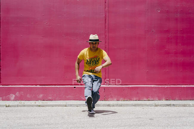 Молодые латиноамериканцы танцуют рядом с розовой стеной на улице — стоковое фото