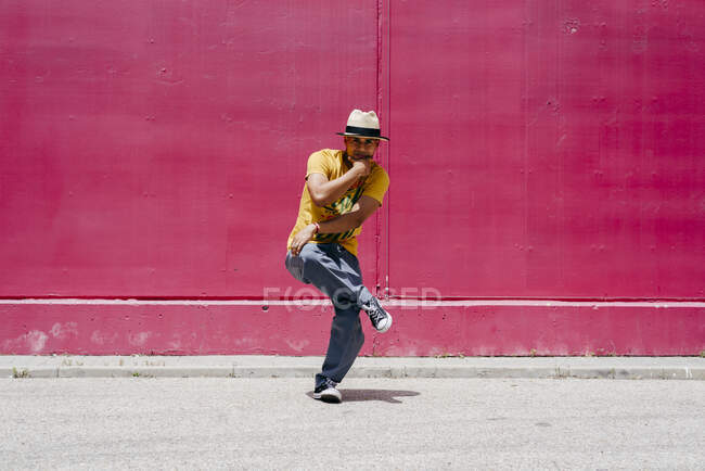 Junge hispanische Männer tanzen in der Nähe einer rosa Wand auf der Straße — Stockfoto