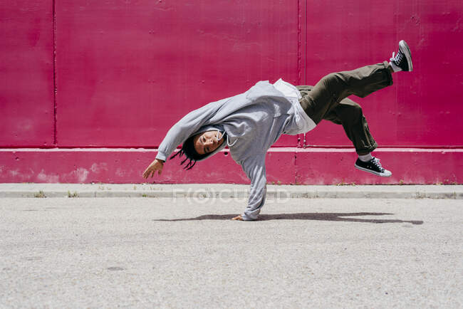 Giovani uomini ispanici che fanno acrobazie vicino a un muro rosa per strada — Foto stock