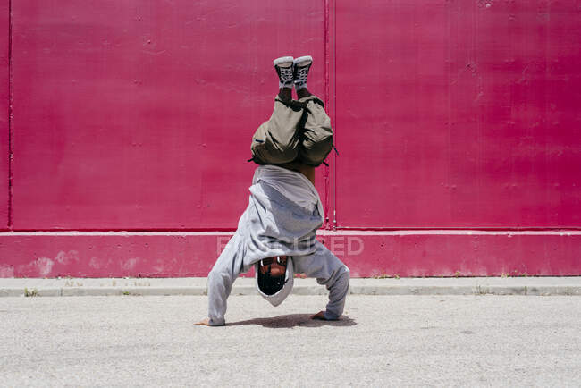 Junge hispanische Männer machen Akrobatik in der Nähe einer rosa Wand auf der Straße — Stockfoto