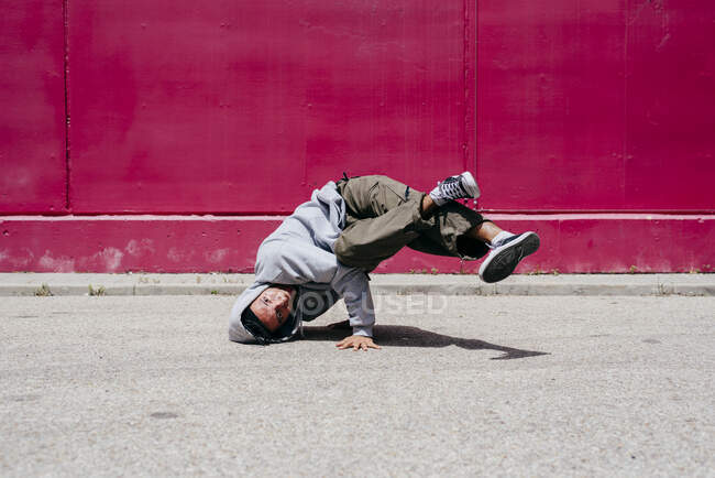 Jeunes hommes hispaniques faisant des acrobaties près d'un mur rose dans la rue — Photo de stock