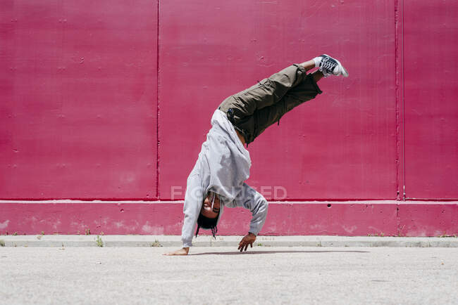 Jovens hispânicos fazendo acrobacias perto de uma parede rosa na rua — Fotografia de Stock