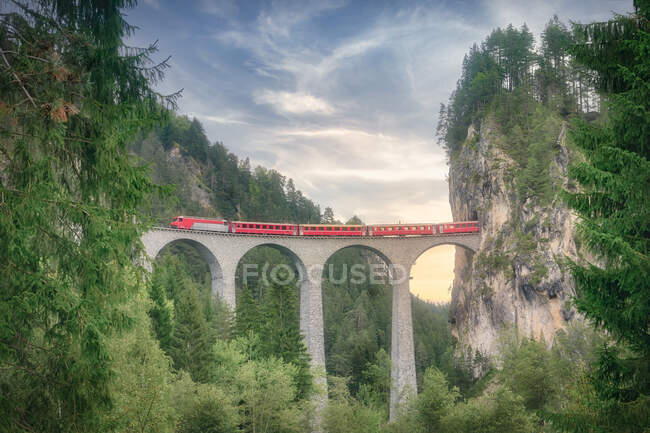 Train on railroad on arched bridge in green mountainous scene, Switzerland — Stock Photo