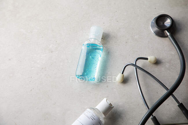 Gel antibacteriano, máscara médica y estetoscopio en la mesa - foto de stock