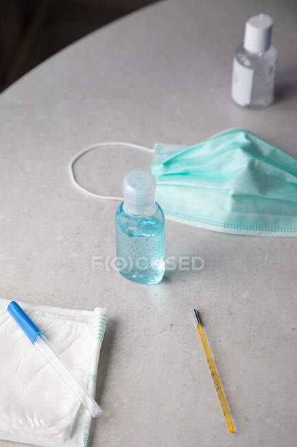 Antibacterial gel and medical mask on table — Stock Photo