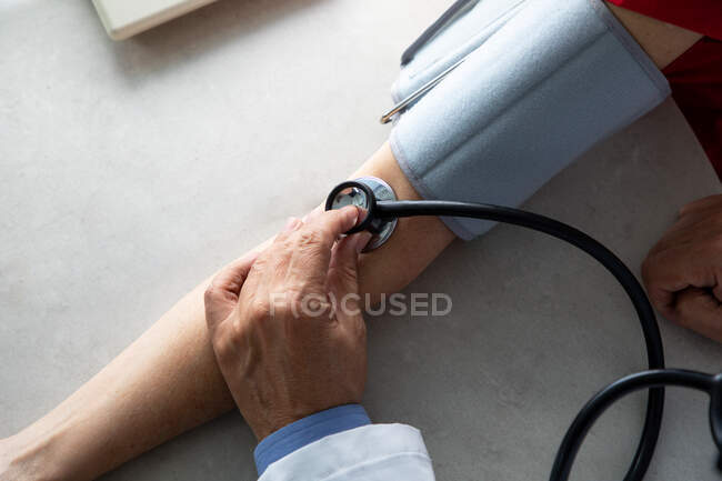 Inyección recortada de médico usando estetoscopio en la mano del paciente - foto de stock