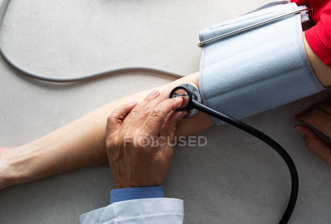 Обрезанный снимок врача со стетоскопом на руке пациента — стоковое фото