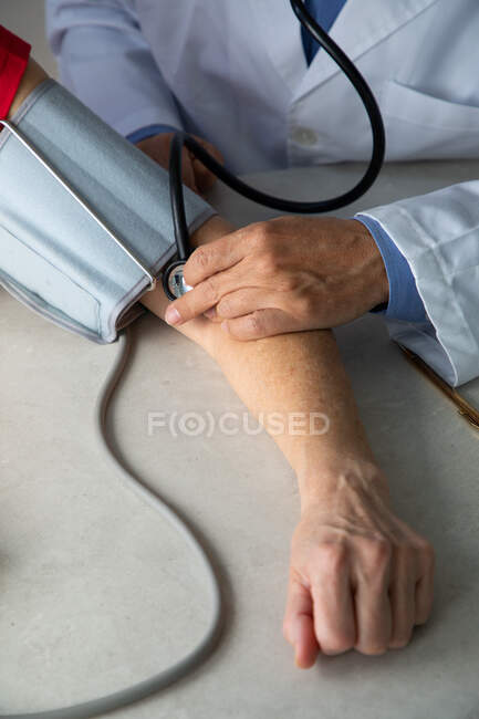 Iniezione ritagliata di medico utilizzando lo stetoscopio sulla mano del paziente — Foto stock