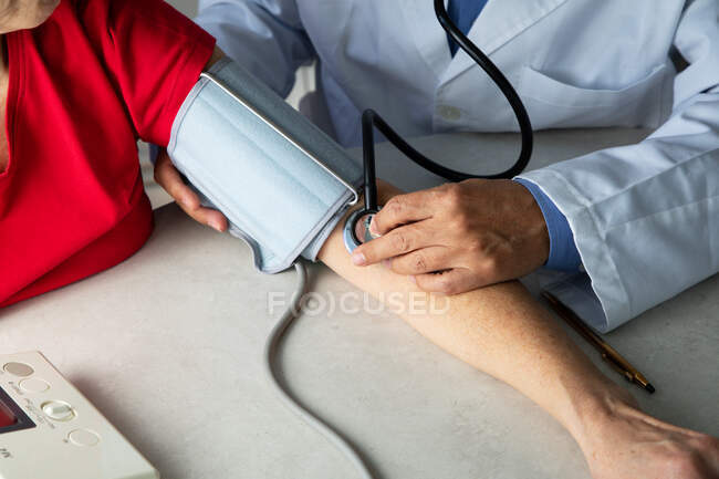 Обрізаний знімок лікаря, що вимірює кров'яний тиск пацієнта з тонометром — стокове фото