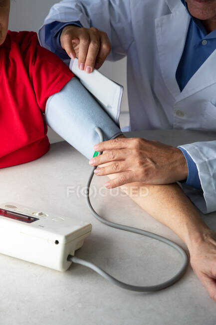 Prise de vue recadrée du médecin mesurant la pression artérielle du patient avec tonomètre — Photo de stock