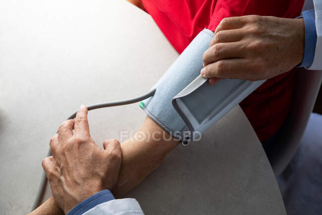 Colpo ritagliato del medico che misura la pressione sanguigna del paziente con tonometro — Foto stock