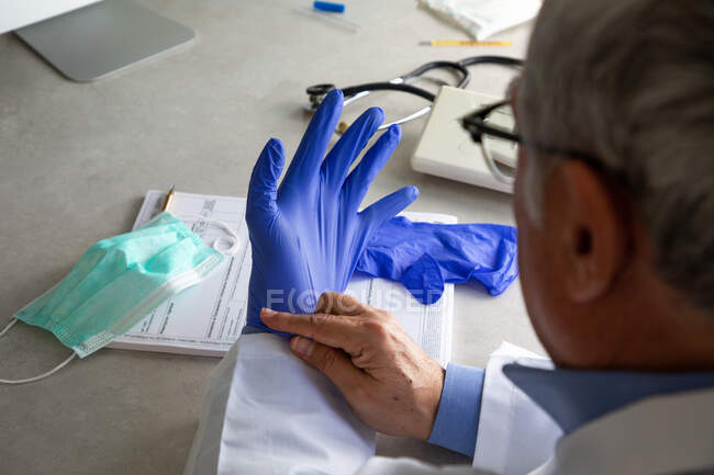Tiro cortado de médico masculino colocando luva protetora em — Fotografia de Stock