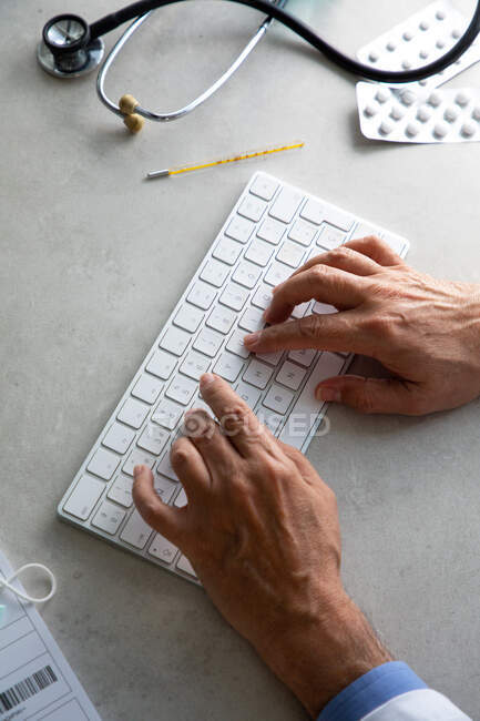 Les mains du médecin masculin tapant sur le clavier de l'ordinateur au bureau de travail — Photo de stock