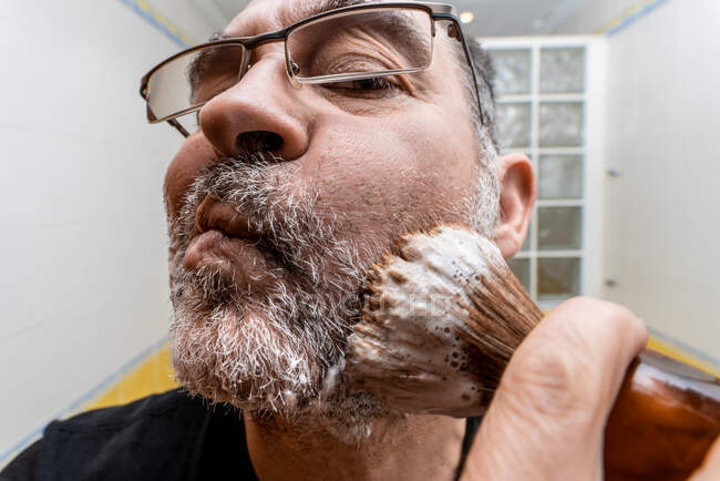 Homem aplicando espuma de barbear com escova — Fotografia de Stock