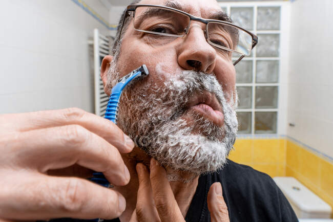 Homme barbu rasage dans la salle de bain, gros plan — Photo de stock