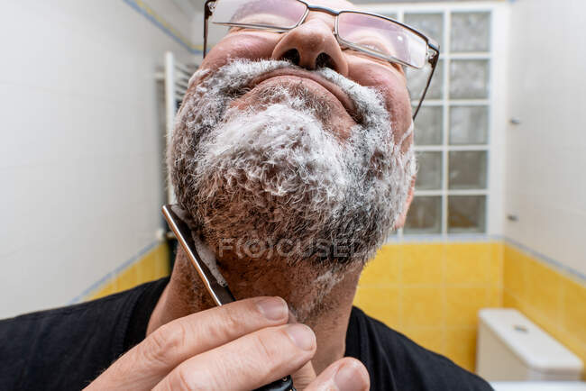 Бородатий чоловік голиться прямою бритвою — стокове фото