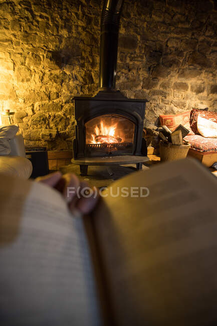 Заблокований анонімний чоловік з книжковим охолодженням у вітальні з палаючим каміном у старому кам'яному будинку в Іспанії. — стокове фото