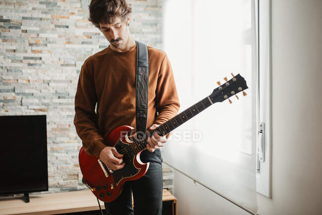 Homme jouant de la guitare à la maison — Photo de stock