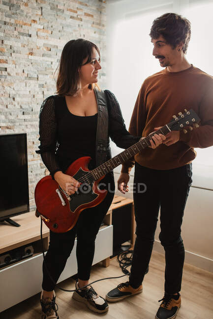 Homem ensinando mulher a tocar guitarra em casa — Fotografia de Stock