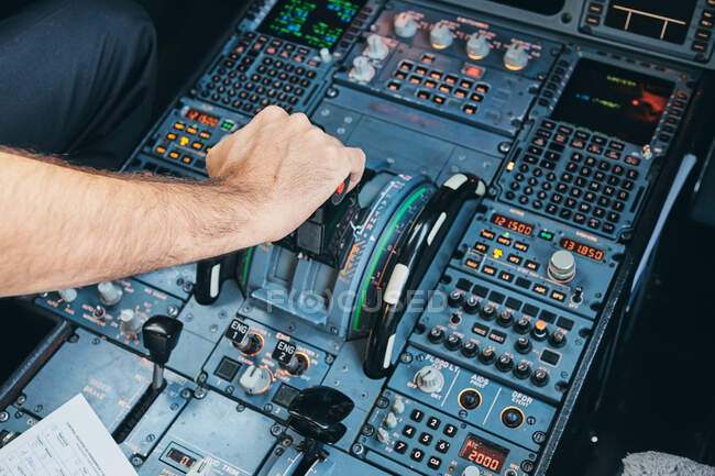 Von oben: anonymer männlicher Pilot drückt Hebel auf dem Armaturenbrett, während er moderne Flugzeuge während des Fluges steuert — Stockfoto