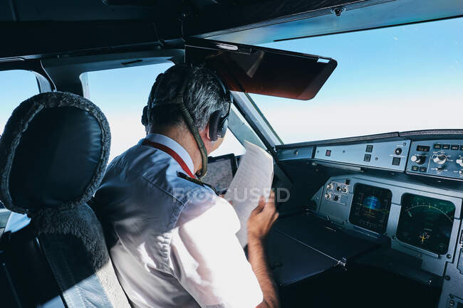 Capitão verificando o documento de voo no cockpit do avião — Fotografia de Stock