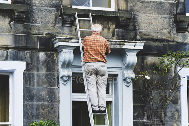 Старший анонімний чоловік ремонтує двері старого особняка — стокове фото
