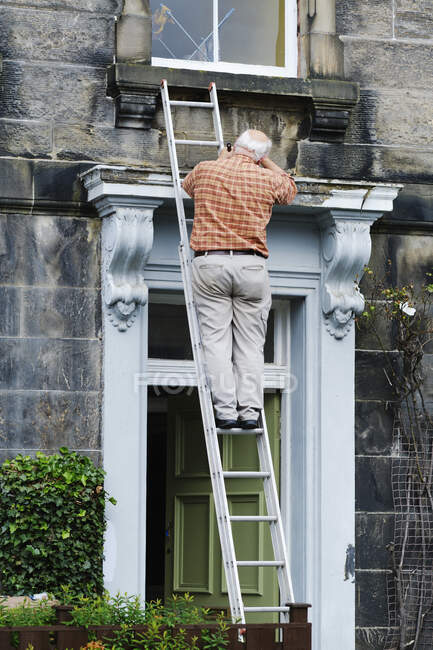 Senior uomo anonimo riparazione porta della vecchia villa — Foto stock